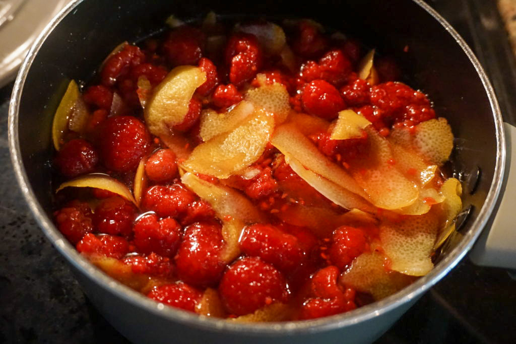 adding the lemon peels and raspberries to the sugar water