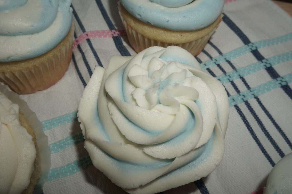 One single vanilla cupcake topped with a flowered baby blue and white vanilla buttercream. 