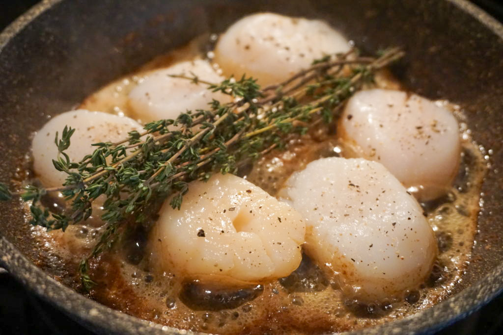 basing the sea scallops with butter and fresh herbs 