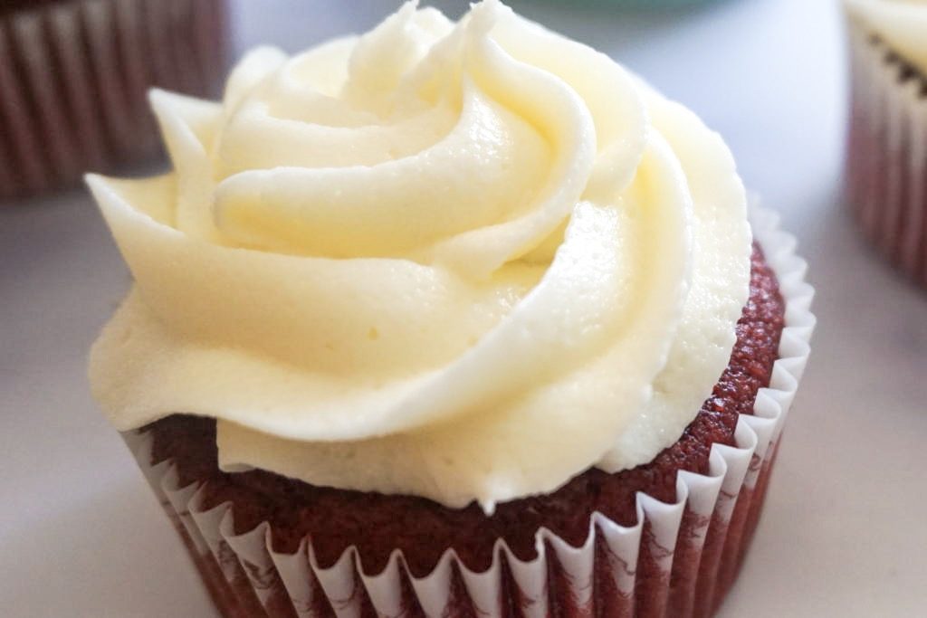 Close up of one red velvet cupcake topped with a silky cream cheese buttercream