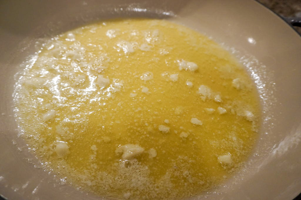 Making the Alfredo sauce melting unsalted butter and adding fresh garlic