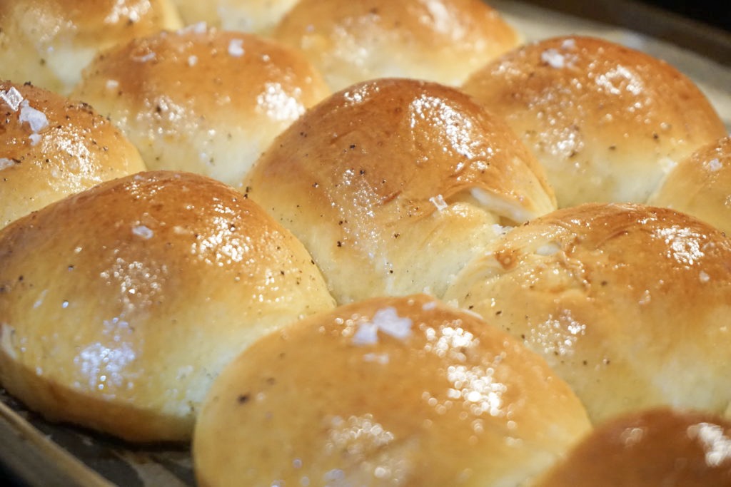 Close-up of the baked brioche dinner rolls with brown butter and flaky sea salt on top