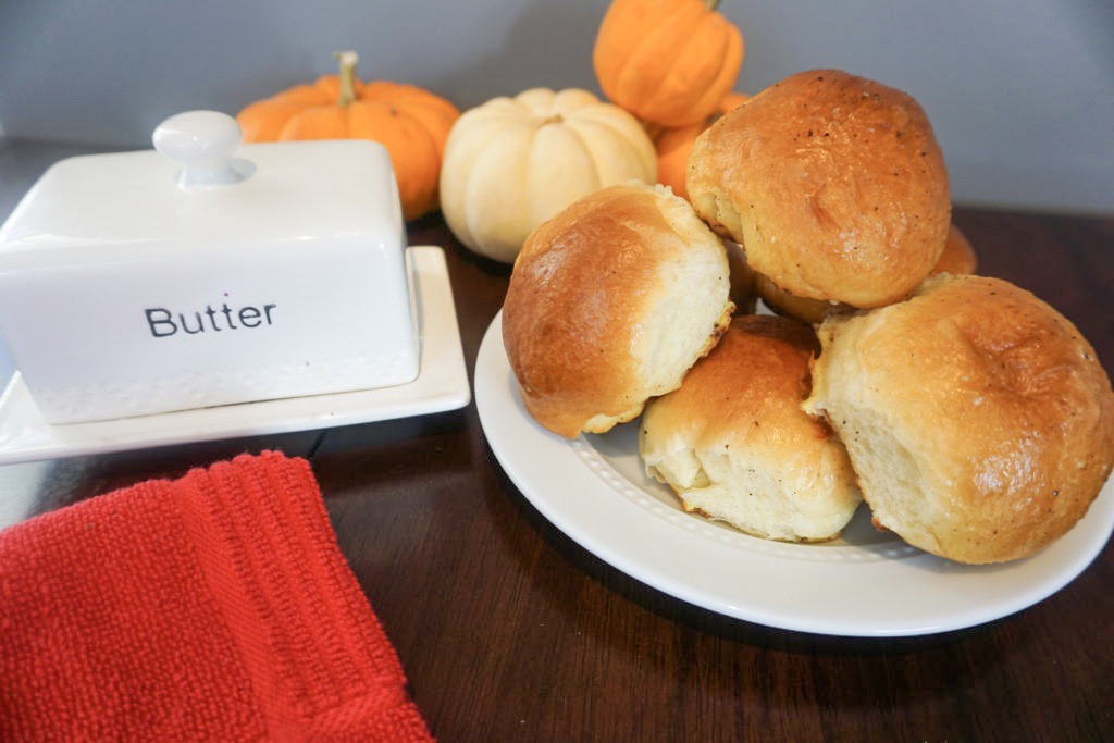 Brioche dinner rolls displayed on a table with butter