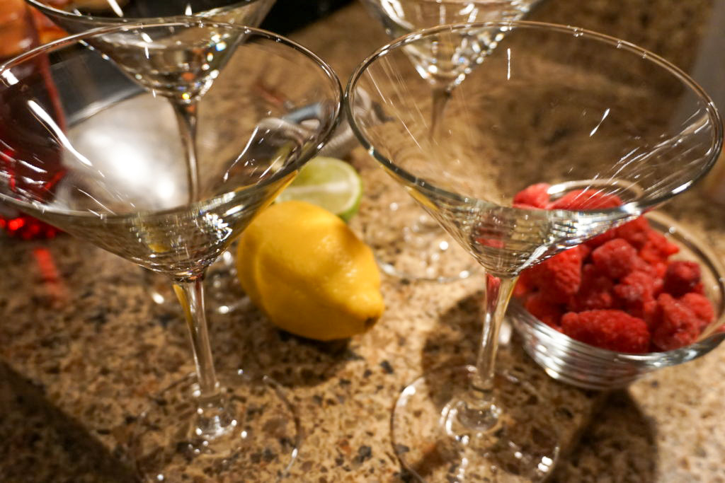 making the martini with martini glasses, citrus, and raspberries 