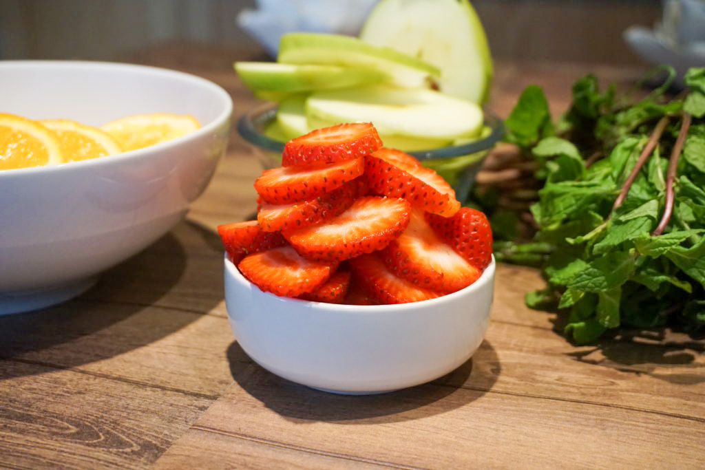 close-up of fresh fruit strawberries, apples, mint, and oranges