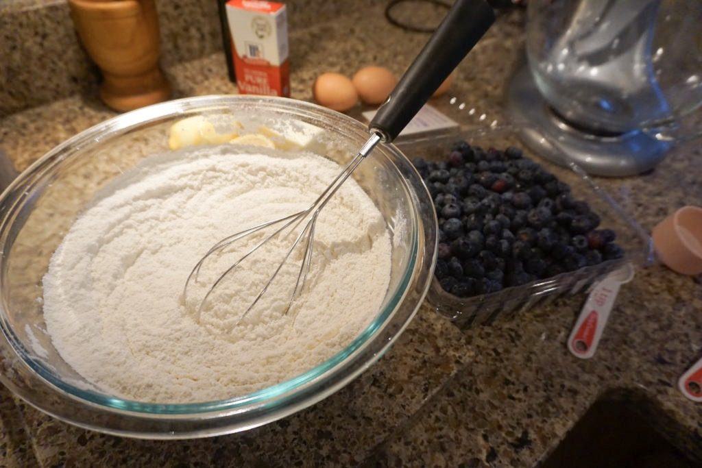 Flour mixture with blueberries in the background