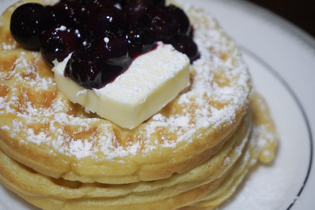 Fluffy waffles with lemon blueberry compote, butter, and powdered sugar 