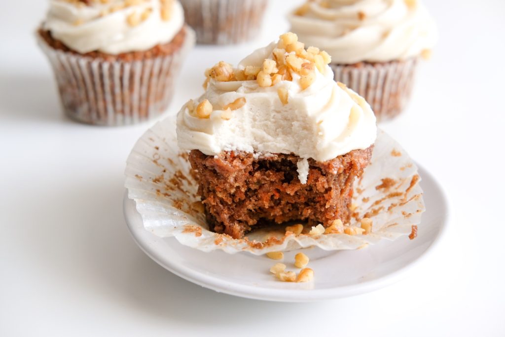 close-up of a bitten vegan carrot cake cupcake with chopped walnuts